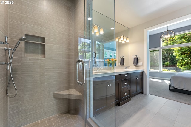 bathroom with double vanity, tiled shower, a sink, and tile patterned flooring