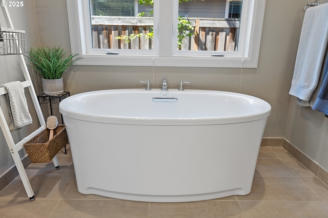full bathroom with baseboards, tile patterned flooring, and a soaking tub