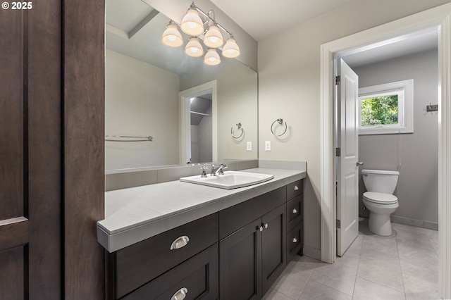 bathroom with tile patterned flooring, vanity, baseboards, toilet, and an inviting chandelier