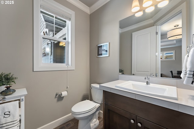half bath featuring vanity, toilet, baseboards, wood finished floors, and ornamental molding