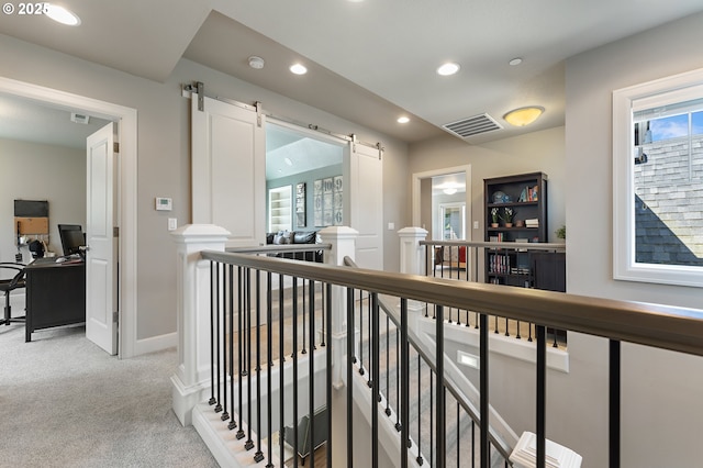 hall with visible vents, recessed lighting, a barn door, light colored carpet, and an upstairs landing