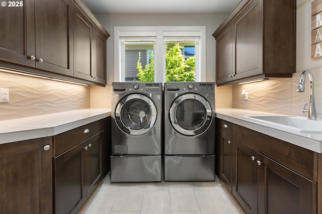 clothes washing area featuring a sink, cabinet space, light tile patterned floors, and washing machine and clothes dryer