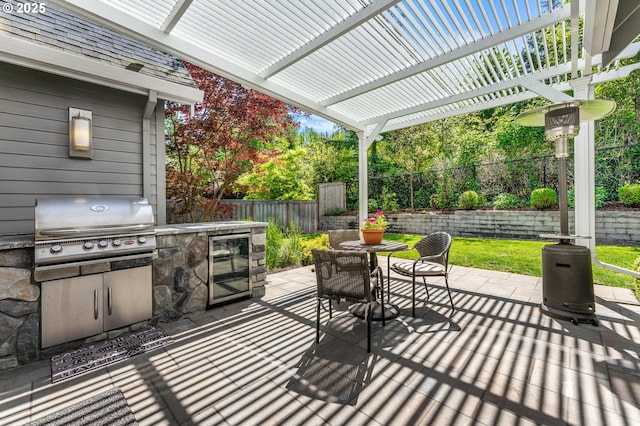 view of patio featuring grilling area, a fenced backyard, wine cooler, an outdoor kitchen, and a pergola
