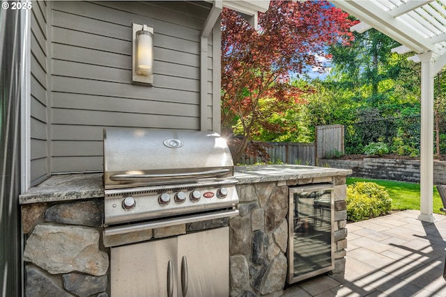 view of patio / terrace with fence, a pergola, exterior kitchen, beverage cooler, and a grill