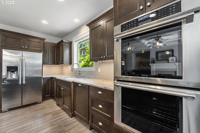 kitchen with backsplash, dark brown cabinetry, appliances with stainless steel finishes, and a sink