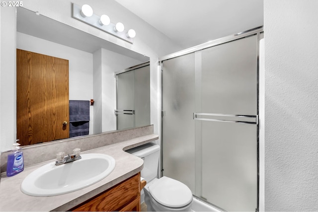 full bathroom featuring toilet, a shower stall, and vanity