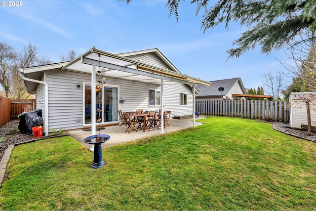 back of house featuring a patio area, a fenced backyard, an outbuilding, and a yard