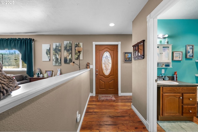 entrance foyer with wet bar, recessed lighting, dark wood finished floors, and baseboards