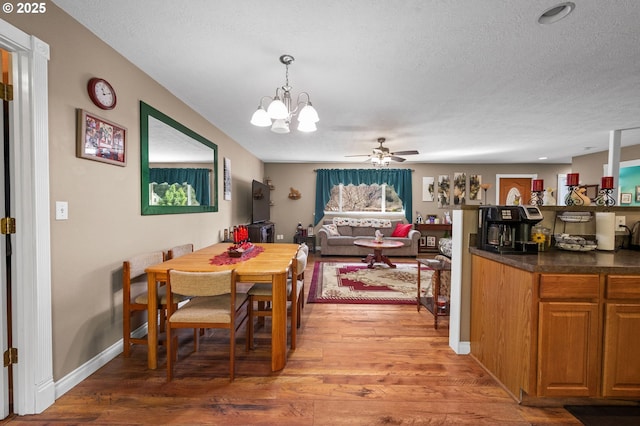 dining area featuring baseboards, light wood-style flooring, and a textured ceiling