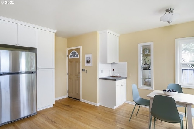 8100 SW 6th Ave, Portland, OR 97219 - kitchen featuring freestanding refrigerator, light wood-style flooring, decorative backsplash, and white cabinets