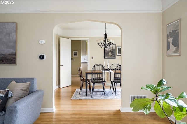 8100 SW 6th Ave, Portland, OR 97219 - dining room with arched walkways, a chandelier, light wood-type flooring, baseboards, and crown molding