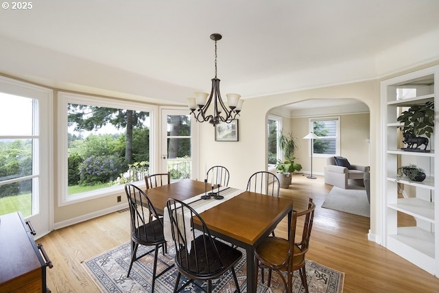 8100 SW 6th Ave, Portland, OR 97219 - dining area featuring arched walkways, light wood-type flooring, a chandelier, and plenty of natural light