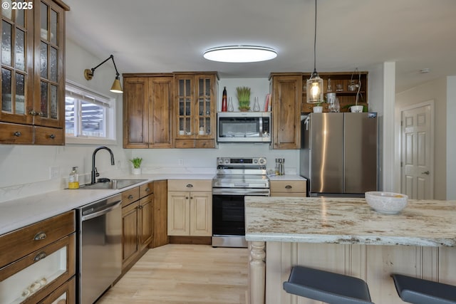156 1st Ave, Coos Bay, OR 97420 - kitchen featuring stainless steel appliances, a sink, light wood-style floors, a kitchen bar, and hanging light fixtures