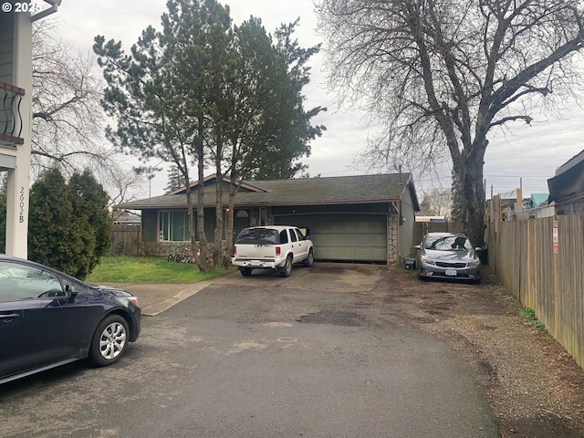 single story home featuring a garage, driveway, fence, and roof with shingles