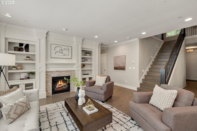 living area featuring baseboards, a tile fireplace, stairs, a textured ceiling, and built in shelves