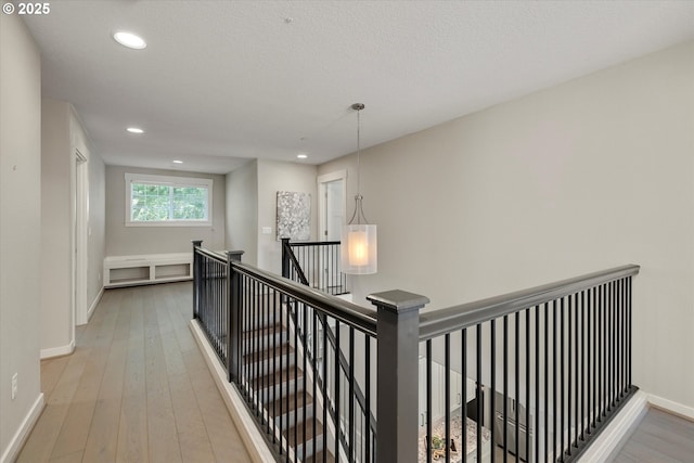 corridor with recessed lighting, light wood-type flooring, an upstairs landing, and baseboards