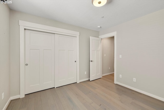 unfurnished bedroom with a closet, light wood-type flooring, and baseboards