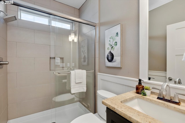 full bathroom with toilet, a wainscoted wall, a shower stall, and vanity