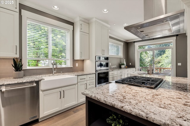 kitchen featuring white cabinets, appliances with stainless steel finishes, extractor fan, and a sink