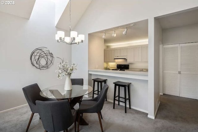 dining area featuring dark carpet, track lighting, vaulted ceiling, and a chandelier