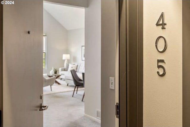 hallway with light carpet and vaulted ceiling