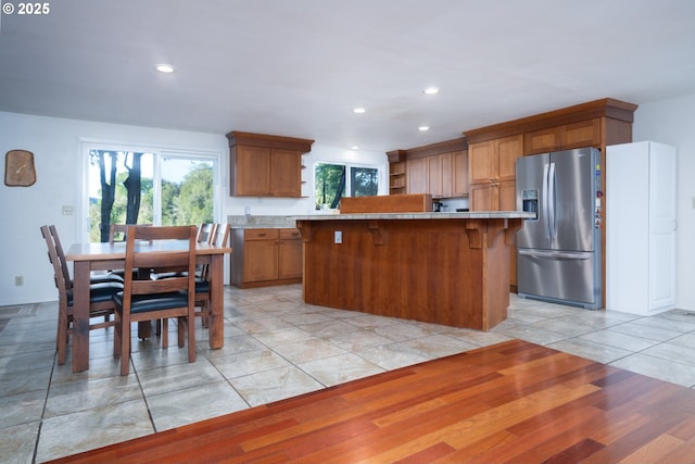 15928 N Umpqua Hwy, Roseburg, OR 97470 - kitchen featuring stainless steel fridge with ice dispenser, brown cabinetry, recessed lighting, a kitchen bar, and a center island