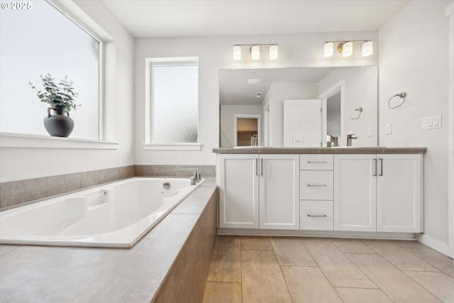 bathroom with tiled bath, vanity, and tile patterned flooring