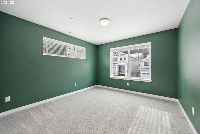 carpeted empty room with a textured ceiling