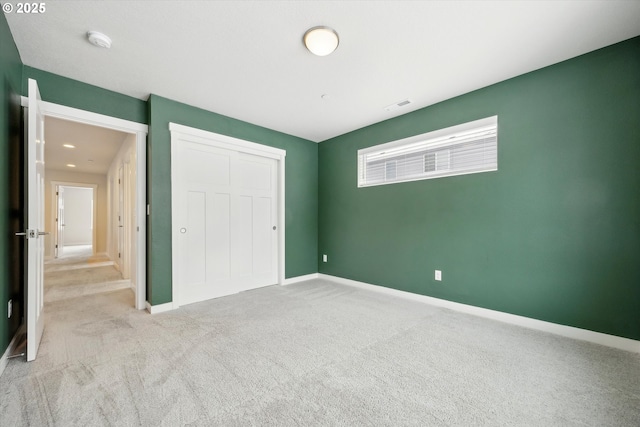 unfurnished bedroom with a closet and light colored carpet