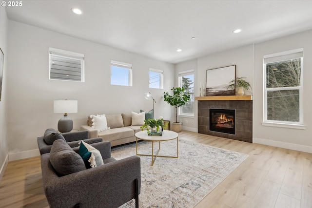 living room featuring light wood-type flooring and a tiled fireplace