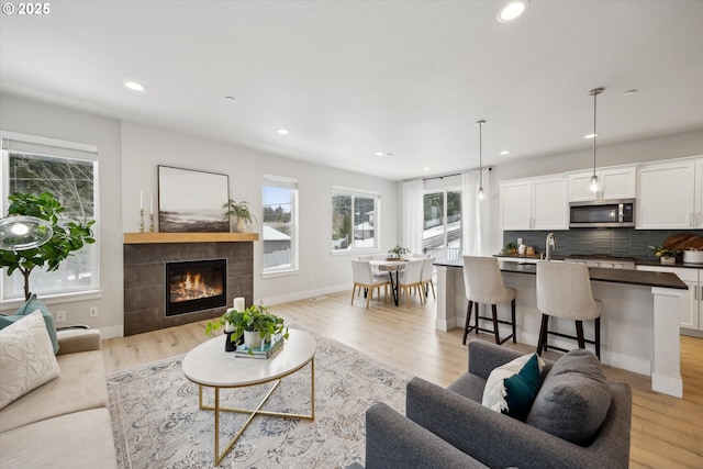 living room with light wood-type flooring and a tile fireplace