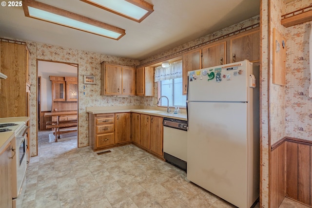 kitchen with visible vents, light countertops, wainscoting, white appliances, and a sink