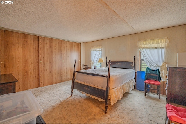 carpeted bedroom featuring wooden walls and a textured ceiling