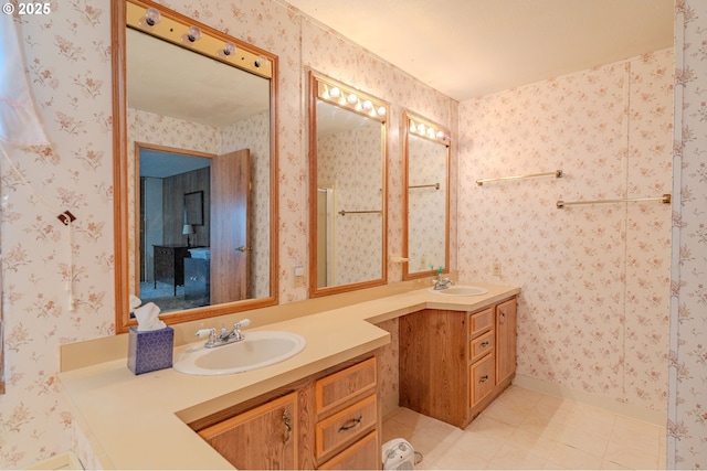 full bath with a sink, two vanities, and wallpapered walls