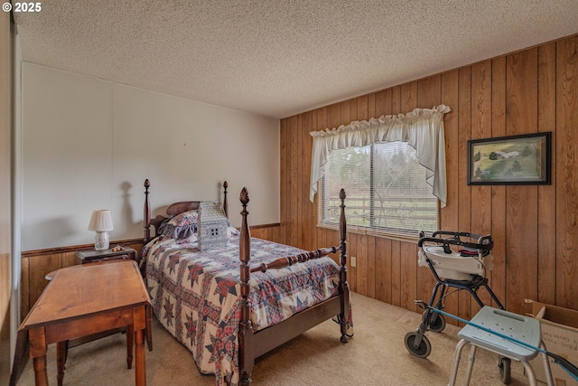 bedroom with a textured ceiling, wood walls, and light carpet