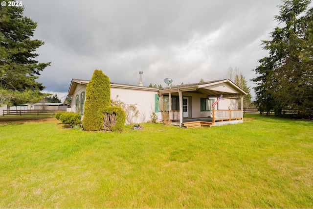 back of property with a lawn and fence