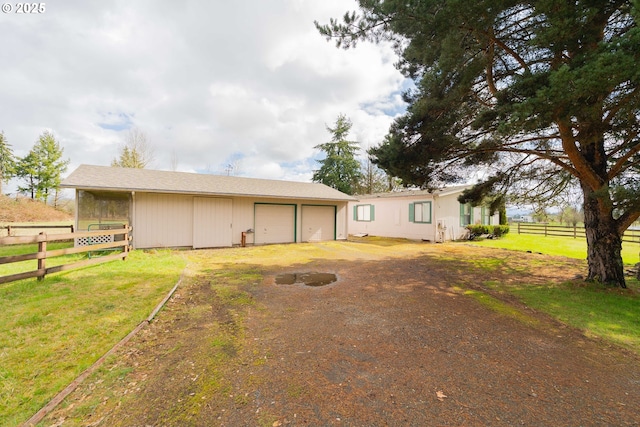 exterior space featuring driveway, an outdoor structure, a garage, and fence