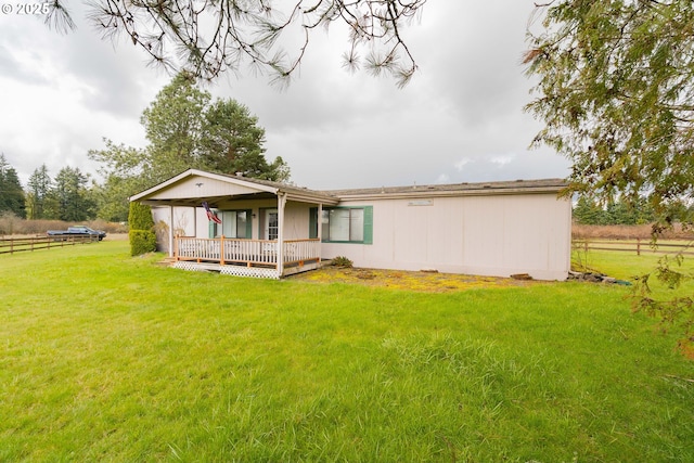 rear view of house with a lawn, a wooden deck, and fence