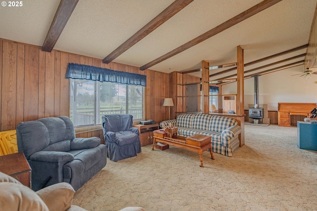 living area featuring wood walls, a textured ceiling, a wood stove, and carpet floors