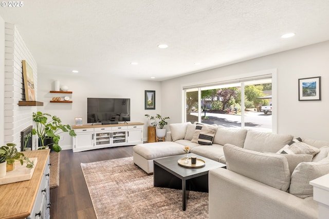 living room with a fireplace, dark wood-style floors, recessed lighting, and a textured ceiling