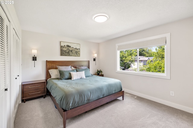 bedroom featuring baseboards, light carpet, and a closet