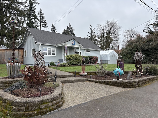 view of front of house featuring a shingled roof and a front yard