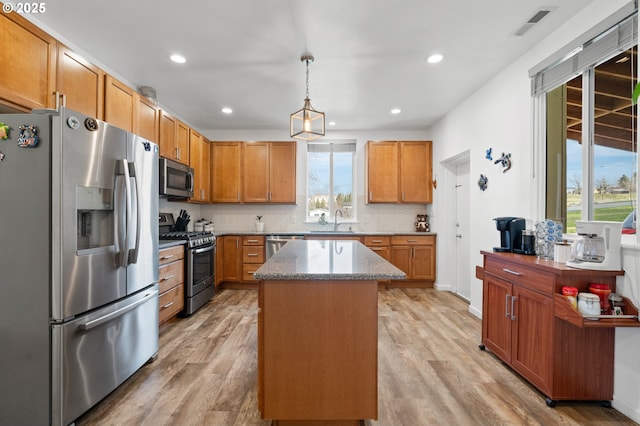 kitchen featuring light wood-type flooring, stone countertops, stainless steel appliances, and a sink