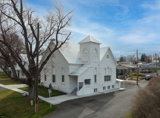 exterior space featuring metal roof, a chimney, and a front lawn