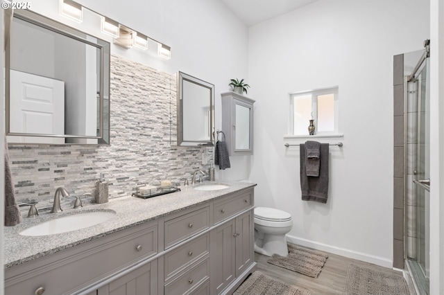 bathroom with an enclosed shower, tasteful backsplash, a sink, and toilet