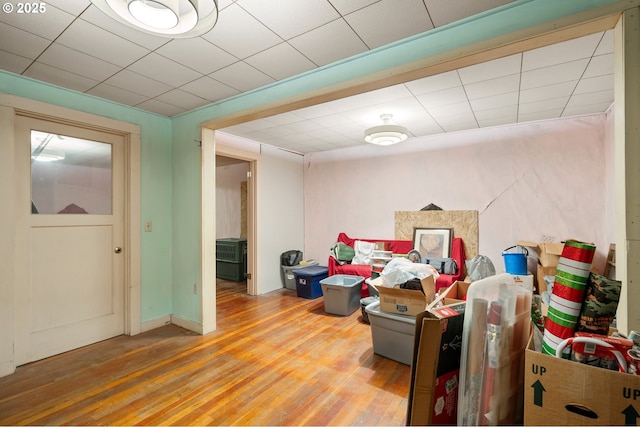 recreation room with a paneled ceiling, light wood-style flooring, and baseboards