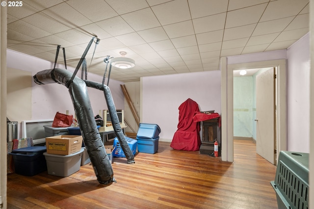 exercise area with a paneled ceiling, heating unit, and wood finished floors