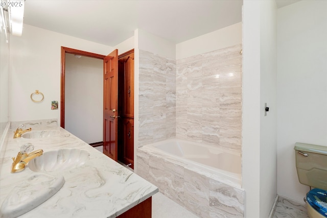 bathroom with toilet, tiled bath, and vanity