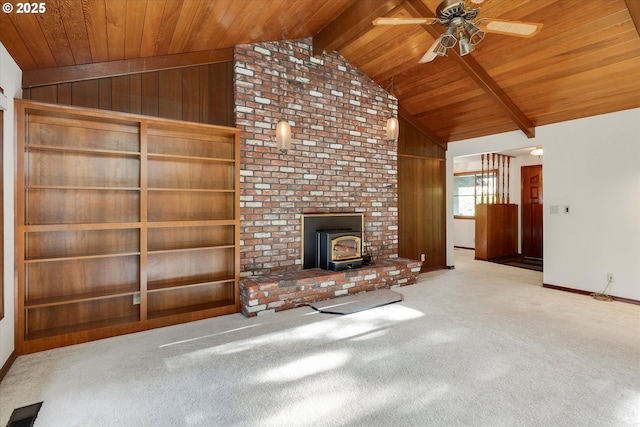 unfurnished living room featuring light colored carpet, wooden walls, and a wood stove