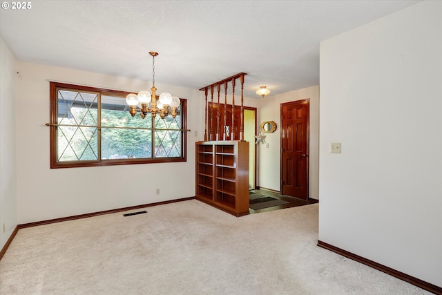 empty room with carpet and a notable chandelier